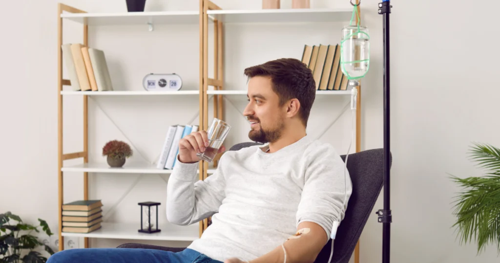 Man receiving IV therapy at home while drinking water in Fountain Valley, CA